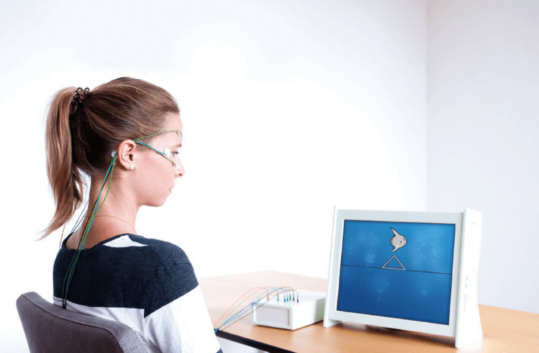 A woman does Neurofeedback therapy to improve with electrodes reading brain activity into a computer screen