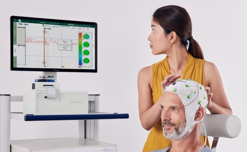 A map wears an EEG cap with brain activity being monitored by a clinician