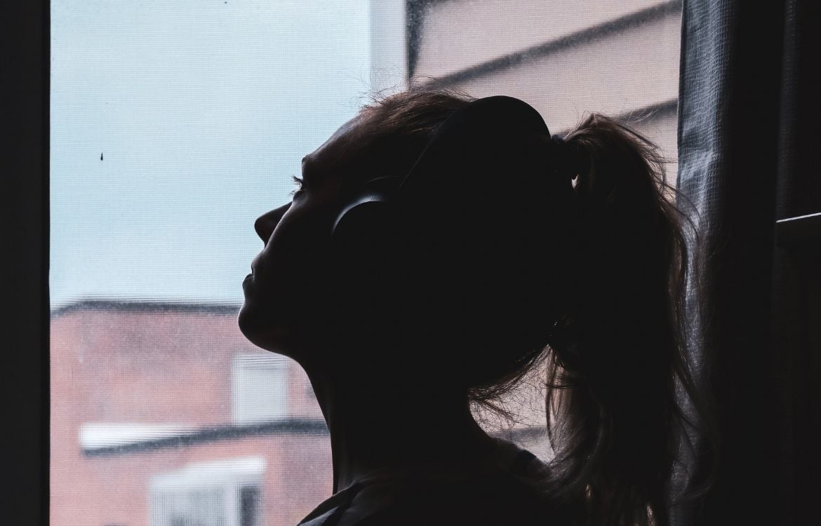 young-female-in-shadows-looking-out-window
